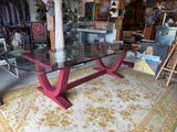 a glass table with a red base in the middle of a room
