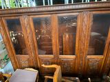 une armoire en bois avec des portes vitrées, devant laquelle se trouve une chaise
