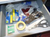 a drawer full of items that include scissors, tape, tape, tape cutters and other items