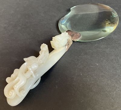 an image of a white jade figurine with a magnifying glass in the background
