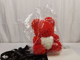 a red teddy bear sitting on top of a white sheet