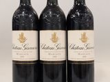 trois bouteilles de vin rouge posées sur une table blanche