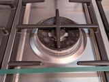 a stainless steel stove top with a glass shelf above it
