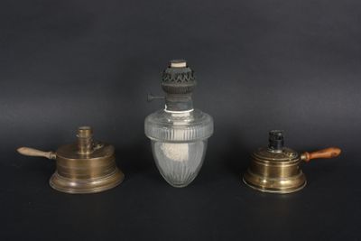three antique brass and glass oil lamps on a black background