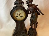 une statue représentant une femme tenant une horloge, posée sur un socle en marbre