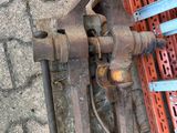 a metal pipe cutter on the ground next to a pallet