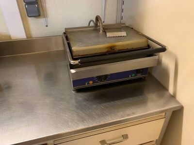 plan de travail en acier inoxydable dans une cuisine professionnelle, sur lequel est posée une friteuse