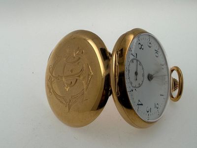 a gold pocket watch sitting on a white surface