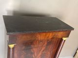 une armoire en bois avec un dessus noir et des poignées dorées