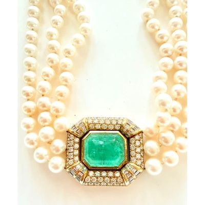 un gros plan sur un collier composé de perles et d'une émeraude