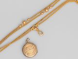 un gros plan d'un collier en or avec un cadenas suspendu à une chaîne