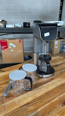 une cafetière posée sur une table en bois à côté d'un mixeur