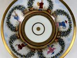 a white plate with a gold rim with a picture of people on it