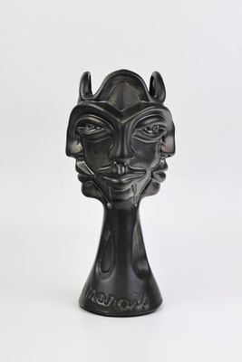 sculpture noire représentant le visage d'une femme avec des cornes, sur fond blanc