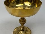 brass footed bowl on pedestal on white surface with white background
