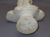 a white statue of a baby laying on the ground with a toothbrush in its mouth
