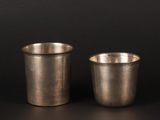 two silver cups sitting next to each other on a black surface