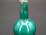 a green glass vase sitting on a black surface