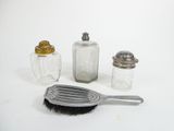 three salt and pepper shakers and a brush on the table