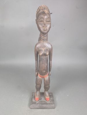 statue d'un homme portant une chaussure rouge, posée sur une surface grise
