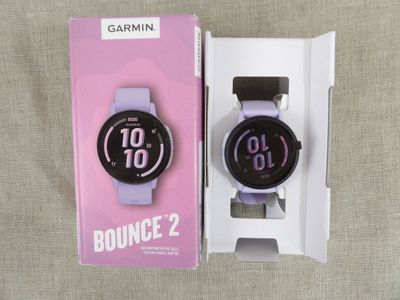 purple and black garmin watch in a box with a white strap