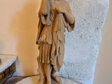 une statue représentant une femme tenant un sac posé sur une table