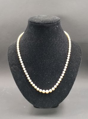 un collier de perles blanches sur un mannequin avec un fermoir en or