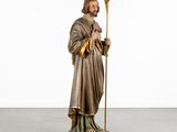a statue of jesus holding a staff in a white room