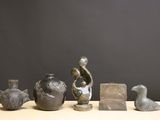 cinq vases différents posés sur une table, sur fond noir