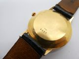 gros plan d'une montre en or sur une surface blanche