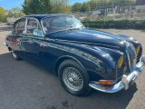 une vieille voiture bleue garée sur un parking près d'une clôture