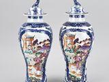 pair of blue and white vases with figures on them sitting on a table