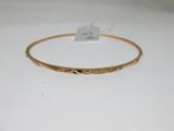 gros plan d'un bracelet en or sur une surface blanche
