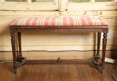 un banc avec un coussin rayé, placé devant une fenêtre