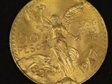 two gold coins with a statue on them on a black surface
