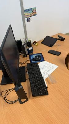 un bureau sur lequel se trouvent un écran, un clavier, une souris et un téléphone portable