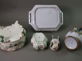 four pieces of porcelain on a table with a clock in the background