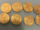 six gold sovereigns of different sizes and shapes on a table