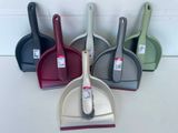 quatre pelles à poussière de couleurs différentes et une balayette posées sur une table