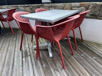 des tables et des chaises sur une terrasse en bois, avec un mur de pierre en arrière-plan