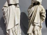 three statues of people in hooded clothing standing next to each other