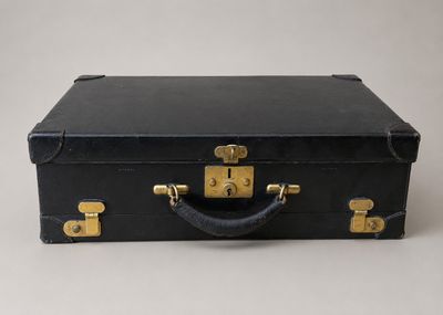 une vieille valise noire posée sur une table blanche