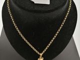 a gold necklace with a blue bead on a black mannequin