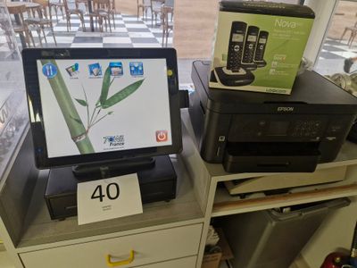un ordinateur portable et une imprimante posés sur un bureau devant une fenêtre