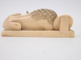 carved ivory figurine of a sleeping lion on a wooden stand
