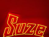 une enseigne au néon rouge sur laquelle est inscrit le mot « suze »