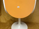 une table orange et blanche, avec un piètement blanc, sur un fond marron