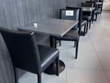 Dans un restaurant, des tables et des chaises sont alignées, et une enseigne est accrochée au mur.