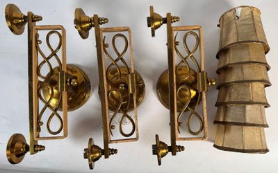 four brass sconces hanging on the wall next to each other