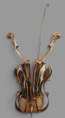 une sculpture dorée représentant un violon sur fond gris